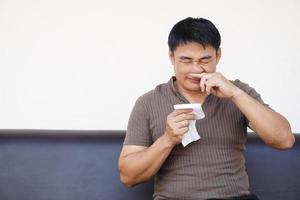 asiático hombre capturas un frío, que produce picor su nariz, sostiene pañuelo de papel papel. concepto, salud problemas, alergia síntomas , estornudar ,tos, líquido nariz. foto