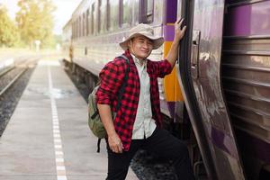 Asian man traveller gets on the local train. Concept, travel by train in Thailand . Railway station ransportation. Alone journey. Weeken, holiday or vacation trip. photo