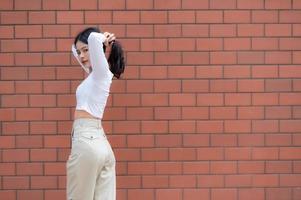 retrato de chica hipster en el fondo de la pared de ladrillo, hermosa mujer asiática posar para tomar una foto, estilo kawaii foto