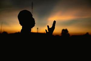 Silhouette Young asian muslim man praying on sunset,Ramadan festival concept photo