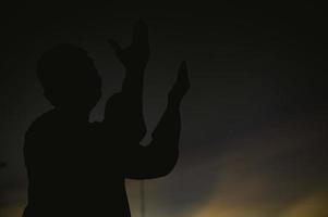 Silhouette Young asian muslim man praying on sunset,Ramadan festival concept photo