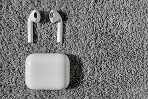 Top view on wireless white headphones on a gray velvet background with free space. Distance learning, work from home or online courses or support system. photo