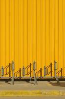 Vertical shot of bike parking near a bright yellow profiled metal wall, fence or warehouse idea, screen background or design articles photo