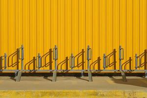 Bicycle parking near a bright yellow profiled metal wall, fence or warehouse idea, background for a screen or design articles photo