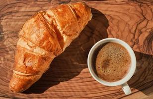 café y cuerno en de madera mesa, francés desayuno idea, soleado brillante día. parte superior ver plano laico con Copiar espacio para texto foto