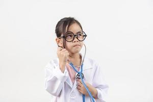 Asia pequeño niña jugando médico aislado en blanco foto