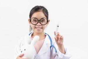 Asia pequeño niña jugando médico aislado en blanco foto