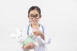 Asia pequeño niña jugando médico aislado en blanco foto