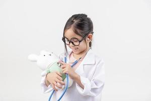 Asia pequeño niña jugando médico aislado en blanco foto