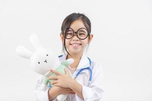 Asia pequeño niña jugando médico aislado en blanco foto