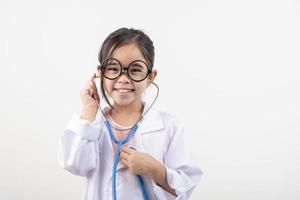 Asia pequeño niña jugando médico aislado en blanco foto