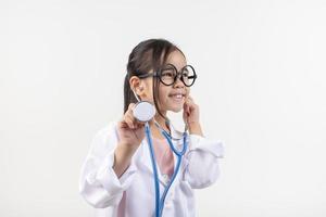 Asia pequeño niña jugando médico aislado en blanco foto