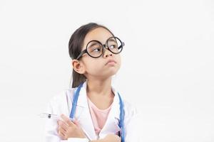 Asia pequeño niña jugando médico aislado en blanco foto