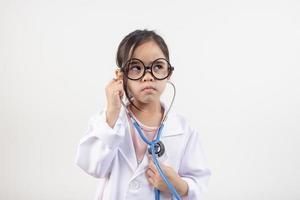 Asia pequeño niña jugando médico aislado en blanco foto