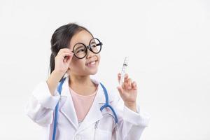 Asia pequeño niña jugando médico aislado en blanco foto