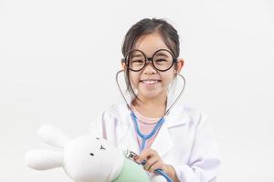 Asia pequeño niña jugando médico aislado en blanco foto