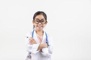 Asia pequeño niña jugando médico aislado en blanco foto