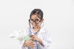 Asia pequeño niña jugando médico aislado en blanco foto