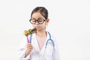 Asia pequeño niña jugando médico aislado en blanco foto