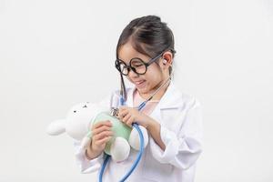 Asia pequeño niña jugando médico aislado en blanco foto