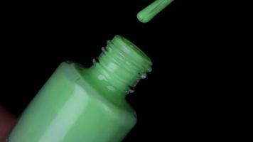 Green neon nail polish on black background video