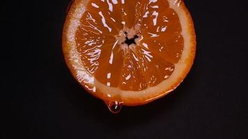 Liquid honey flows down slowly from an orange ring on a black background video