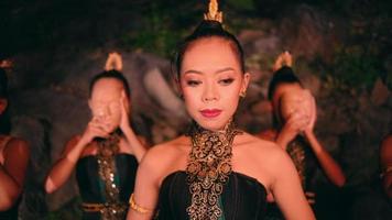 un asiatique femme en marchant parmi une groupe de femmes portant bambou masques avec souriant visages dans de face de le rochers video