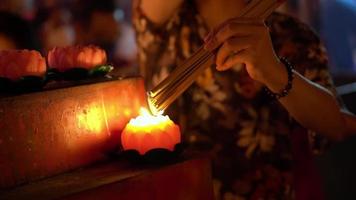 Select focus the hand hold the incense stick and burn with lotus candle in night at Chines temple video