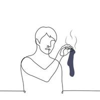 man with disgust on his face holding a stinky sock with his fingertips - one line drawing vector. concept find a dirty sock vector