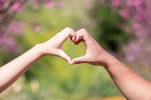 male and female couple showing their hands up to form heart symbol to show friendship love and kindness because heart is symbol of love. male and female couple showing their love with heart symbol photo