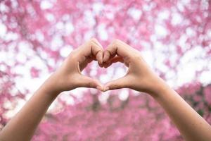 young woman shows her hands above her head making  heart symbol to show friendship love and kindness because heart is symbol of love. Young woman showing love with heart symbol from her hand photo