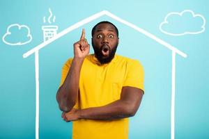 Man is amazed to have bought a house. Cyan background photo