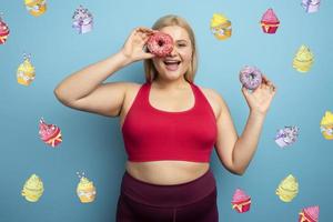 Fat woman eats sweet instead of do gym. Cyan background photo