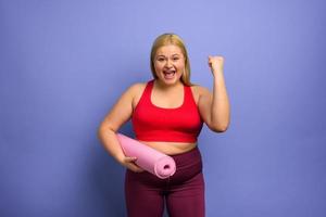 Fat girl does gym at home. satisfied and successfully expression. purple background. photo