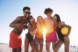 grupo de amigos jugando a playa voleo a el playa. mañana, luz de sol. foto