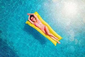 Girl in swimsuit who tan in a swimming pool photo