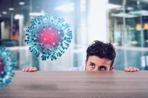 Man is afraid of the covid19 virus and he is hidden rear a desk photo