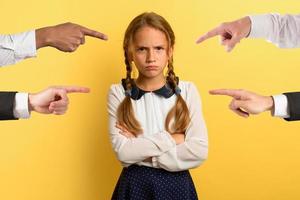 Young girl is unhappy and angry because she is accused. yellow background photo