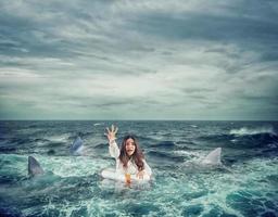 Businesswoman with lifebelt surrounded by sharks asks help photo