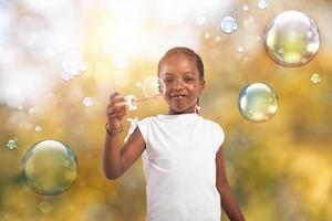 Afro child play with soap bubble outdoor with a sunny day photo