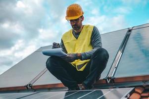 Man works on renewable energy system with solar panel for electricity and hot water photo