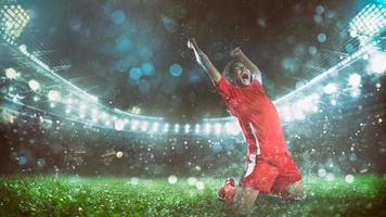 Soccer striker in red uniform rejoices for the victory at the stadium photo