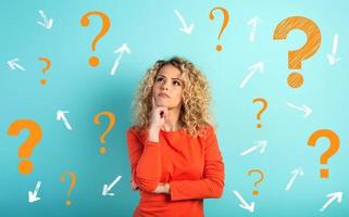 Confused and pensive expression of a girl with many questions . cyan colored background photo