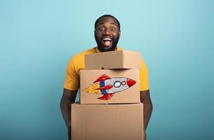 Happy man holds a lot of received packages. Cyan background photo