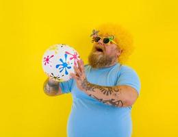 Fat man with wig in head and sunglasses have fun with a ball photo