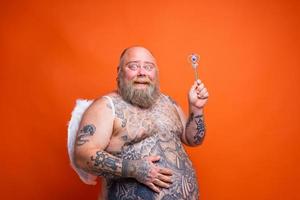 Fat happy man with beard ,tattoos and wings acts like an magic fairy photo