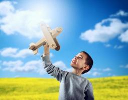 niño obras de teatro con un de madera juguete avión foto