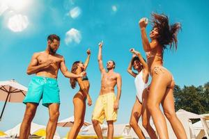 Group of friends in swimsuit dance music in a swimming pool photo