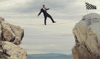 Business concept of businessman who overcome the problems reaching the flag on a rope photo