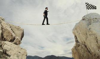 Business concept of businessman who overcome the problems reaching the flag on a rope photo